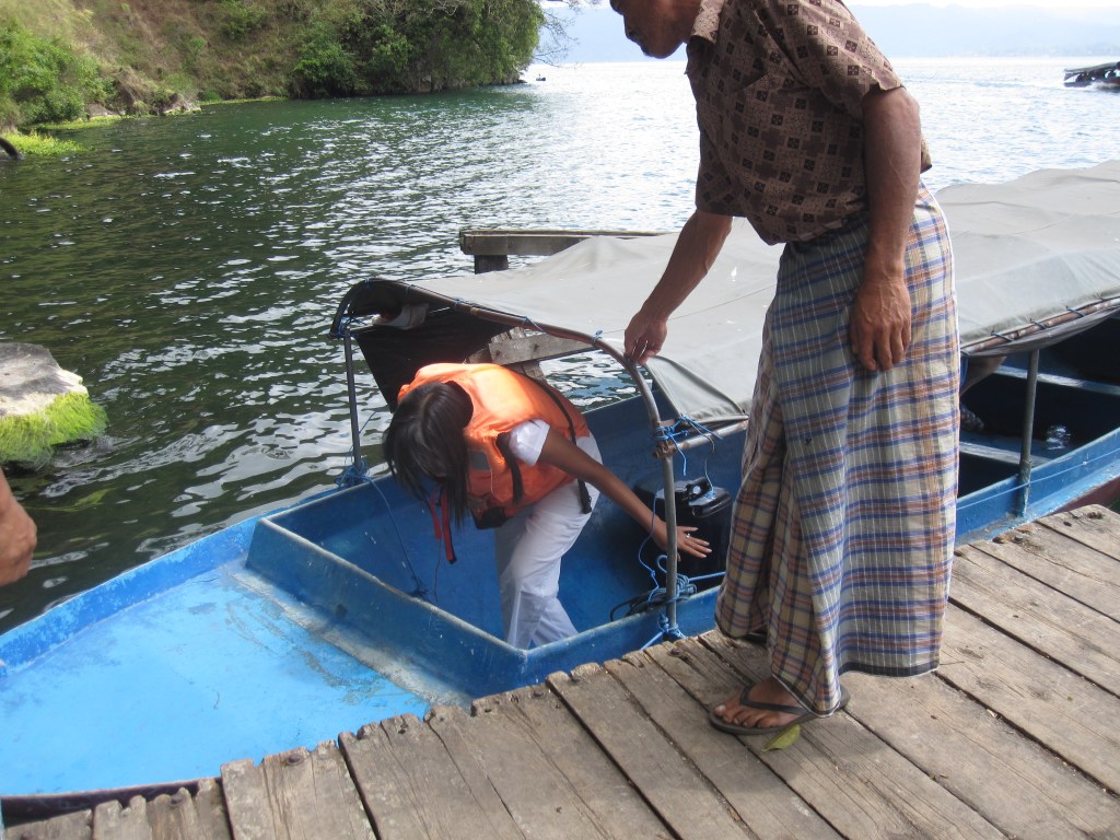 Traveler bersama warga lokal berjalan keluar dari sampan menuju pintu masuk Desa Trunyan di tepi Danau Batur.