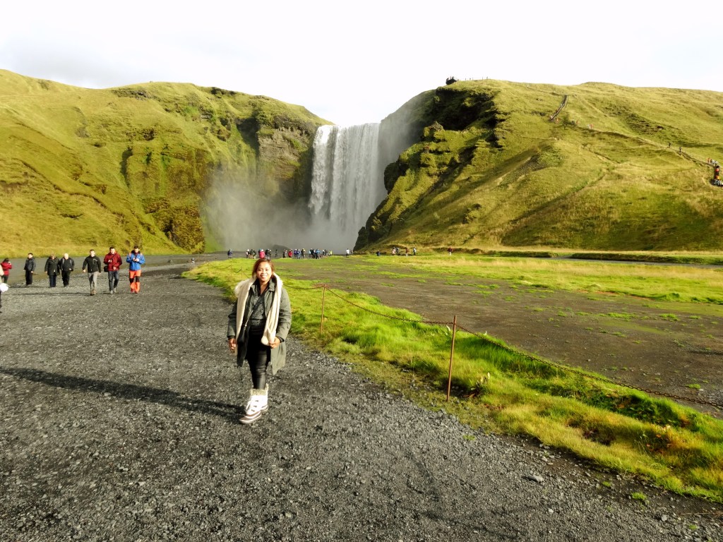 Berdiri di depan Skógafoss Waterfall Iceland dengan latar air terjun megah dan panorama alam