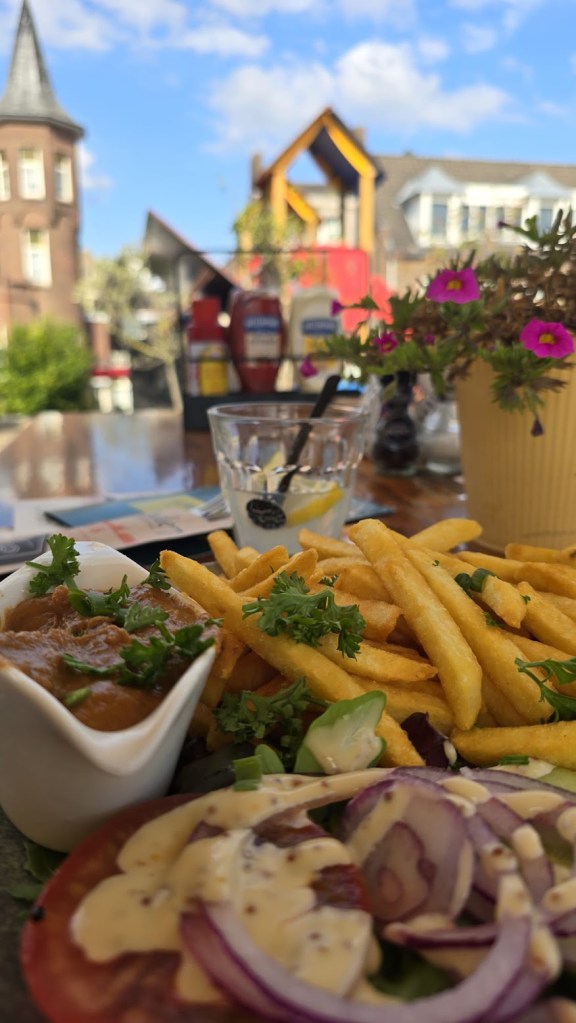 Patat oorlog khas Belanda: kentang goreng tebal dengan saus satay kacang, mayonaise, dan bawang bombay, disajikan dipring, kalau makan di dalam warung 