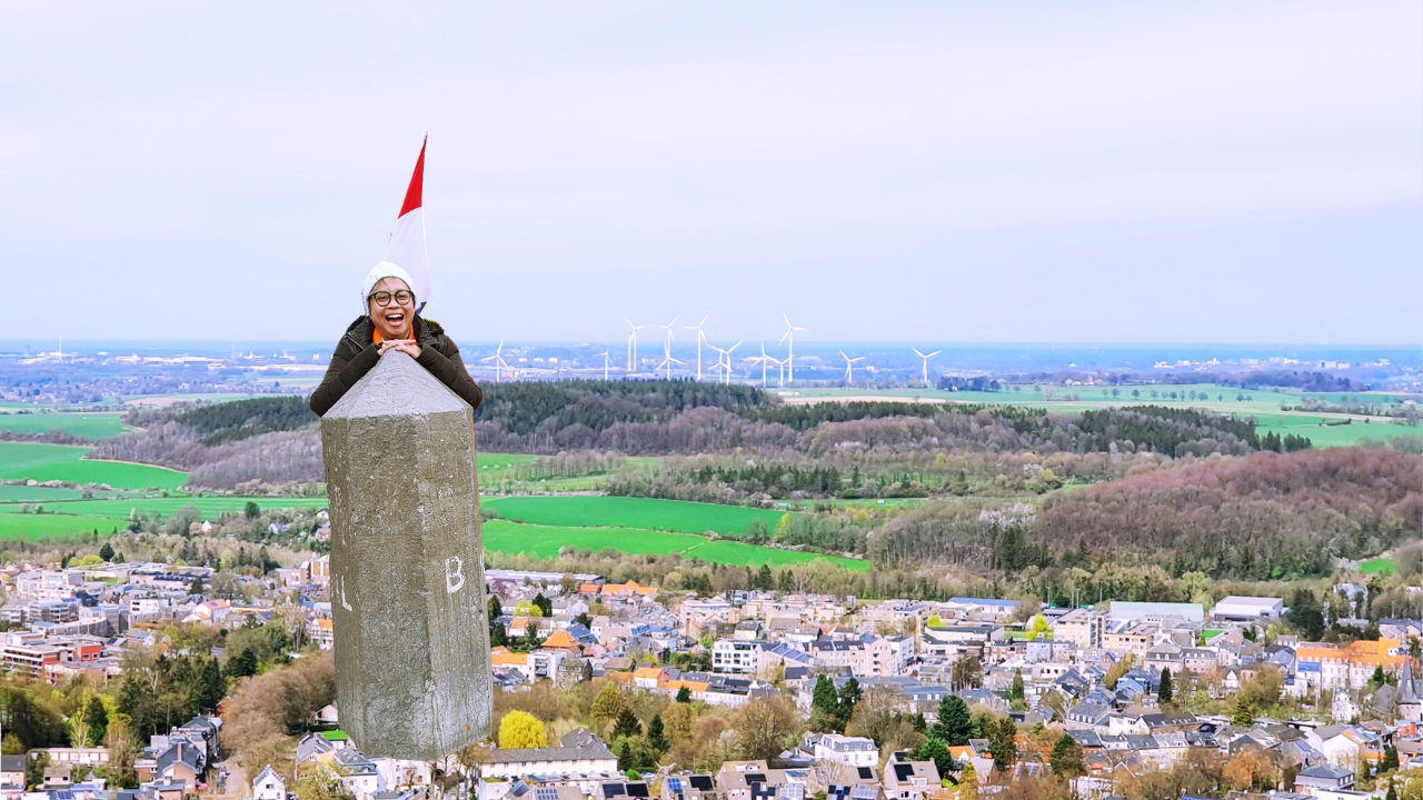 Elly Afriani, Tour Leader Belanda, berdiri di Drielandenpunt Vaals dengan pemandangan panorama tiga negara.